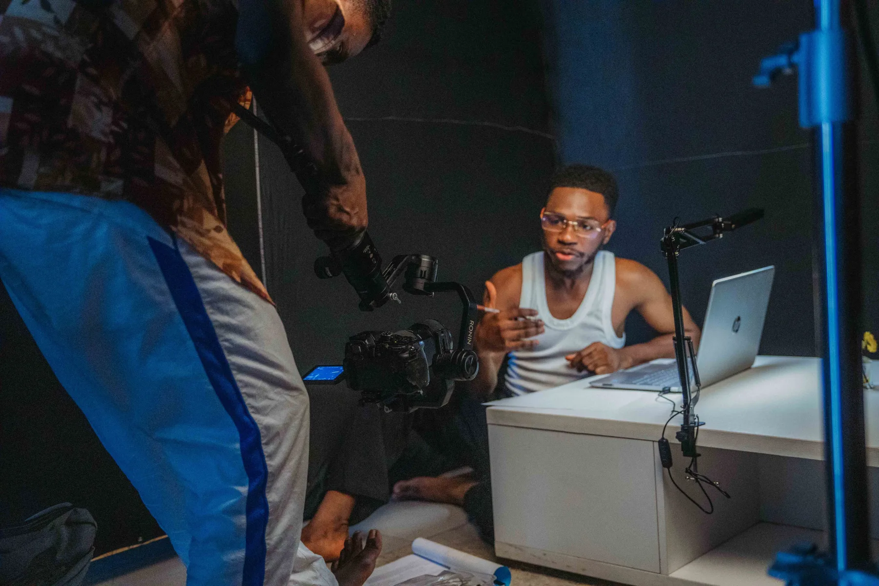 Two creators working with a video camera, laptop, and microphone in a recording studio
